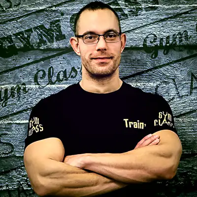 Edző karba tett kézzel áll a teremben.