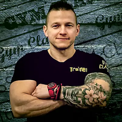 Edző pózol karra tetoválással.