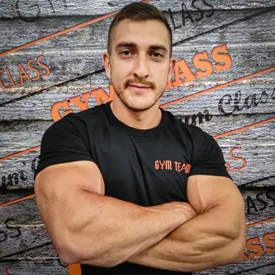 Férfi edző karba tett kézzel edzőteremben.