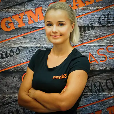 Nő, edzőruha, edzőterem fal előtt.