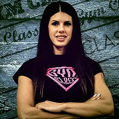 Mosolygó nő edzőteremben, keresztbe tett karral.