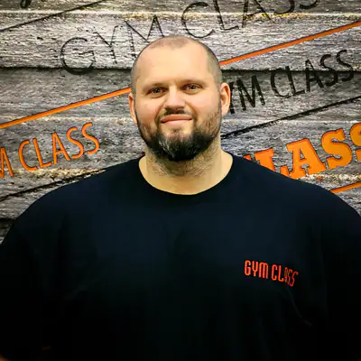 Mosolygó férfi, edzőterem fal előtt.